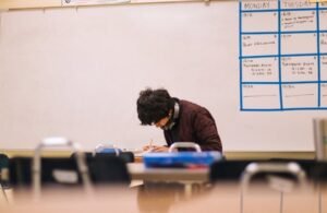 A high school student studying and solving problems in a classroom setting.